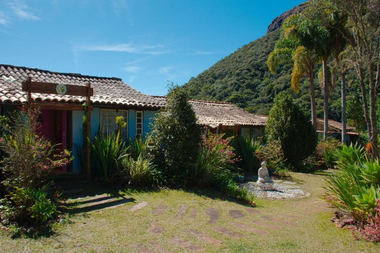 Casas da pousada com jardim e a montanha ao fundo